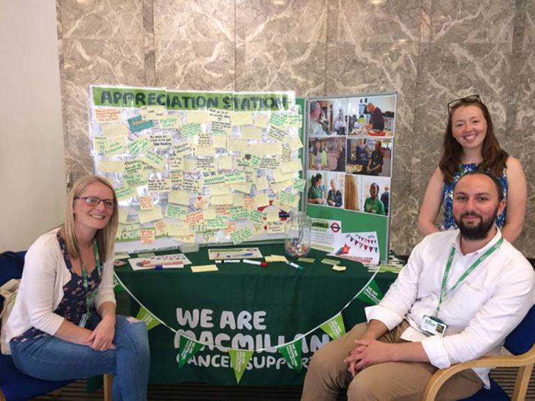 Three Macmillan volunteers with their charity's 'appreciation station' and thank you messages.