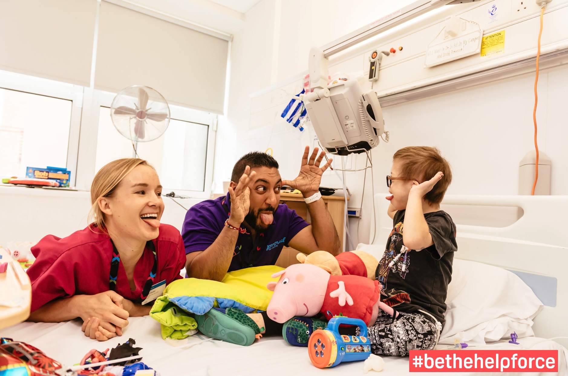 Picture of HelpForce volunteers making child in hospital bed laugh