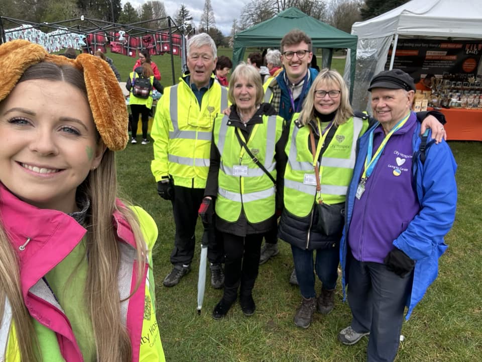 Sam's selfie with a group of City Hospice volunteers in high vis jackets at an event
